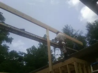 Carpenter setting a ridge beam over a new addition frame — Ice Dam Removal by Roofing Brothers in Bomont