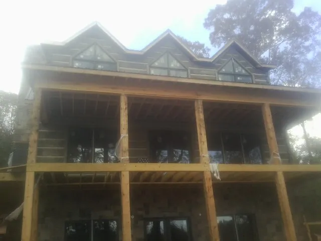 Dormers and porch framing on a large log home under construction — Roof Coating work by our crew in Bomont