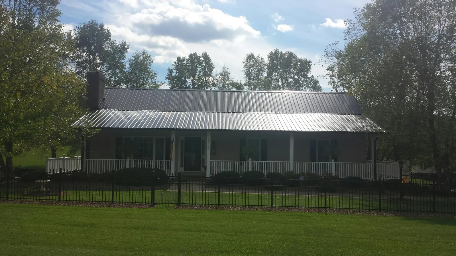 Gray metal roof on a brick ranch with a full width front porch — Gutter Guard Installation work by our crew in Bomont