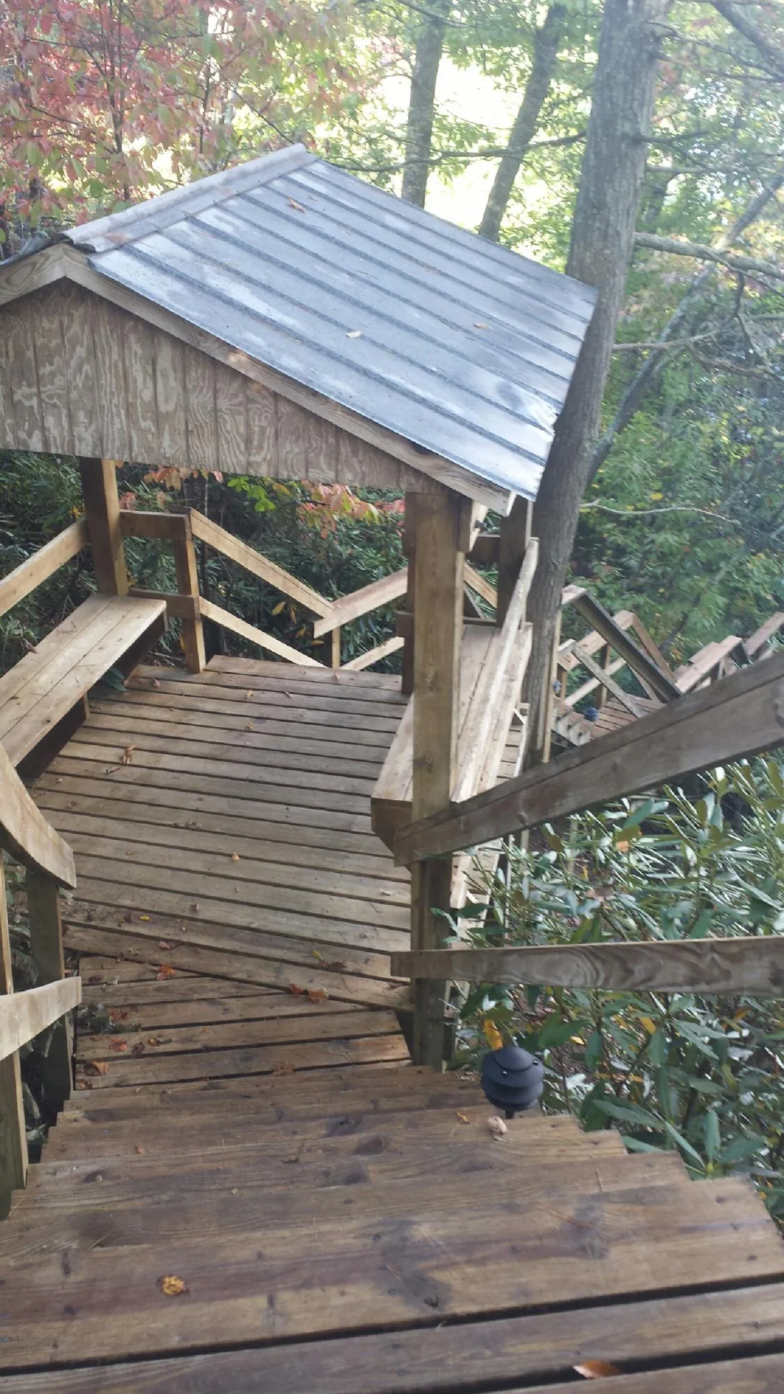 Metal roofed shelter over wooden steps on a wooded walkway — Skylight Repair & Installation work by our crew in Bomont