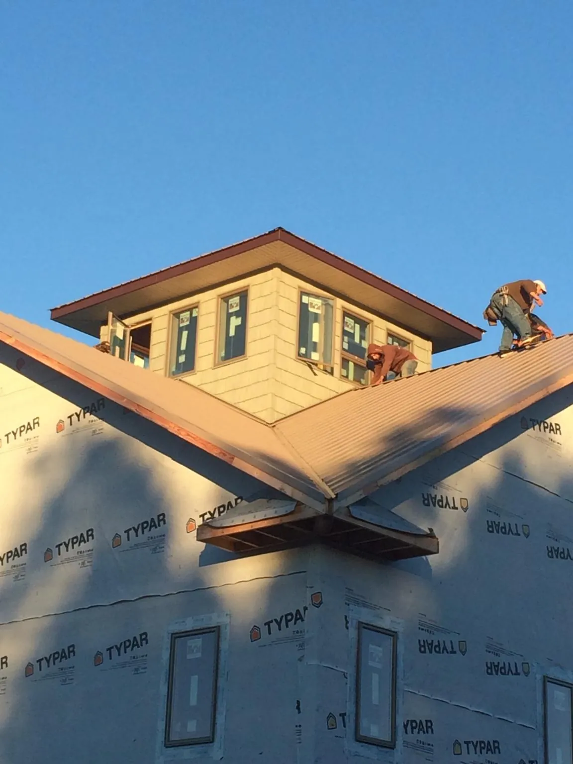 Roofers working around a rooftop cupola on a new metal roof at sunset — Roof Waterproofing in Bomont by Roofing Brothers